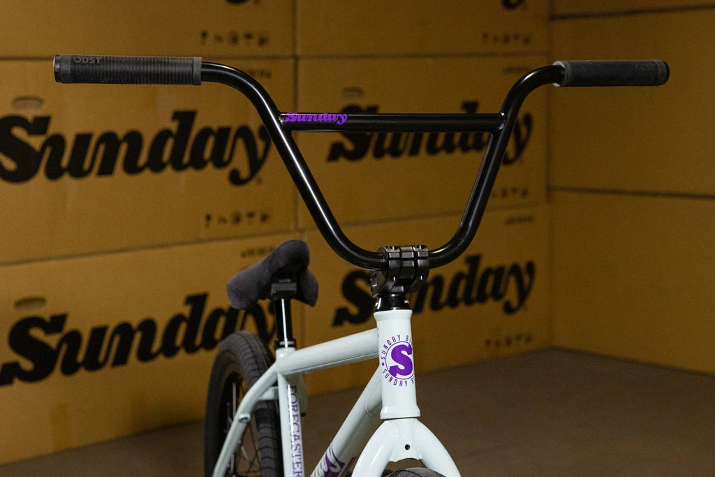 Gros plan d'un guidon noir de vélo BMX Sunday sur cadre blanc.