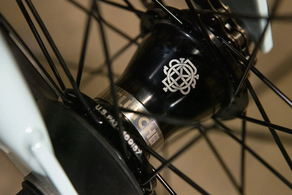 Gros plan d'un moyeu de roue BMX noir avec logo gravé et détails techniques.
