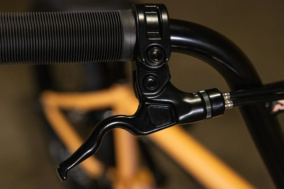Gros plan d'un levier de frein noir monté sur un guidon de vélo BMX.