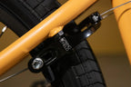 Gros plan d'un tendeur de chaîne Spring Field noir sur un cadre de vélo BMX jaune.