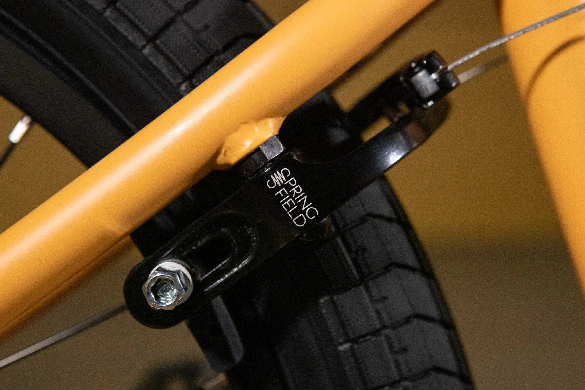 Gros plan d'un tendeur de chaîne Spring Field noir sur un cadre de vélo BMX jaune.