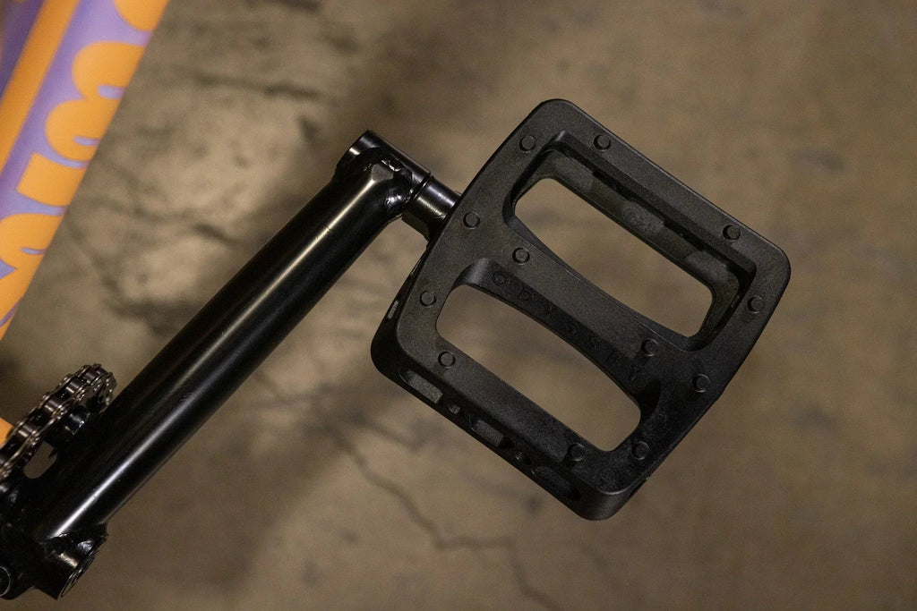 Gros plan d'une pédale de vélo BMX noire en plastique avec picots antidérapants.