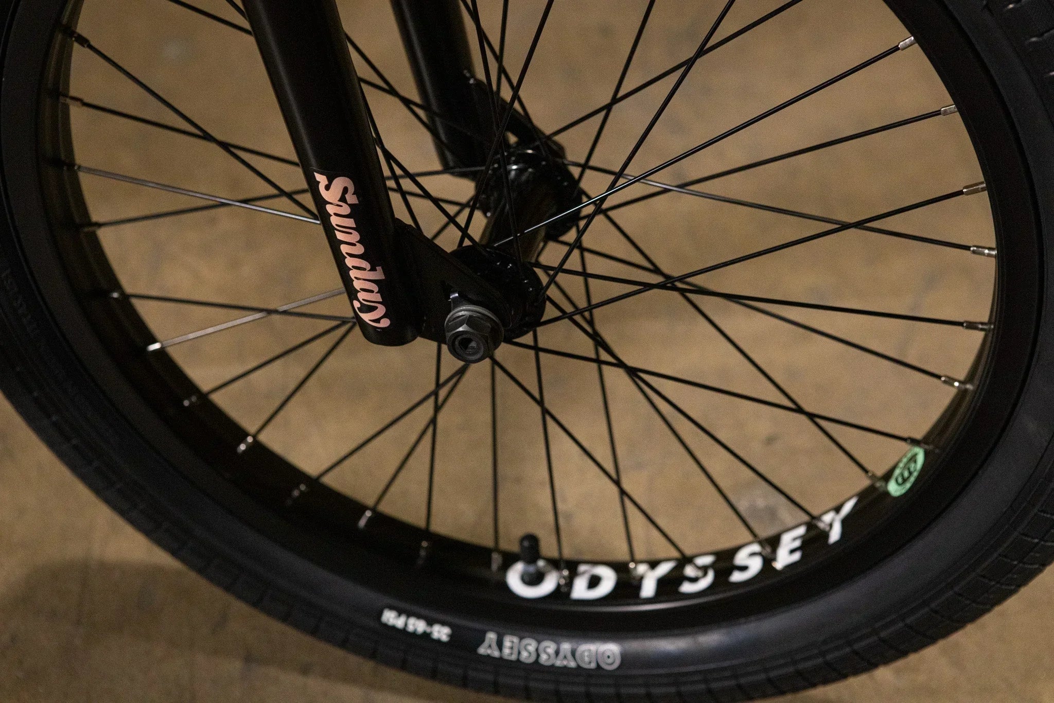 Gros plan d'une roue de vélo BMX avec pneu Odyssey et fourche Sunday noire.