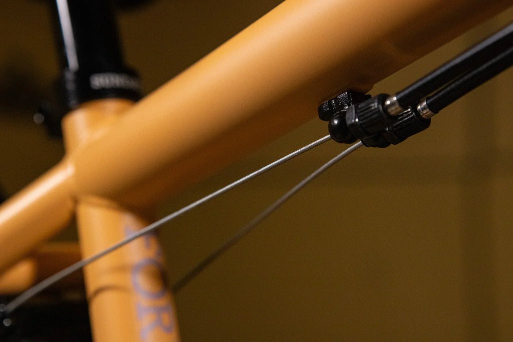 Gros plan du câble de frein sur le cadre jaune d'un vélo BMX