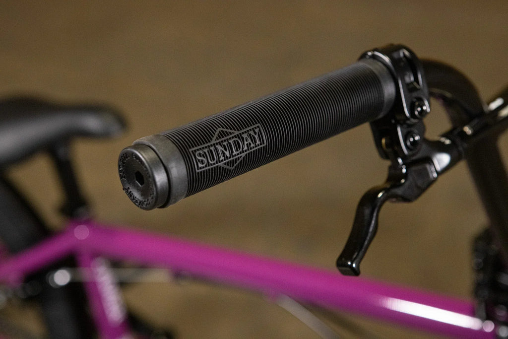 Gros plan d'une poignée de guidon noire Sunday sur un vélo BMX violet