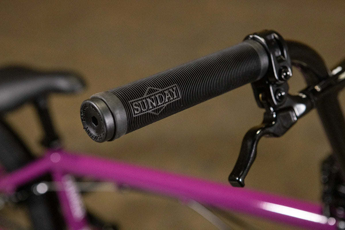Gros plan d'une poignée de guidon noire Sunday sur un vélo BMX violet