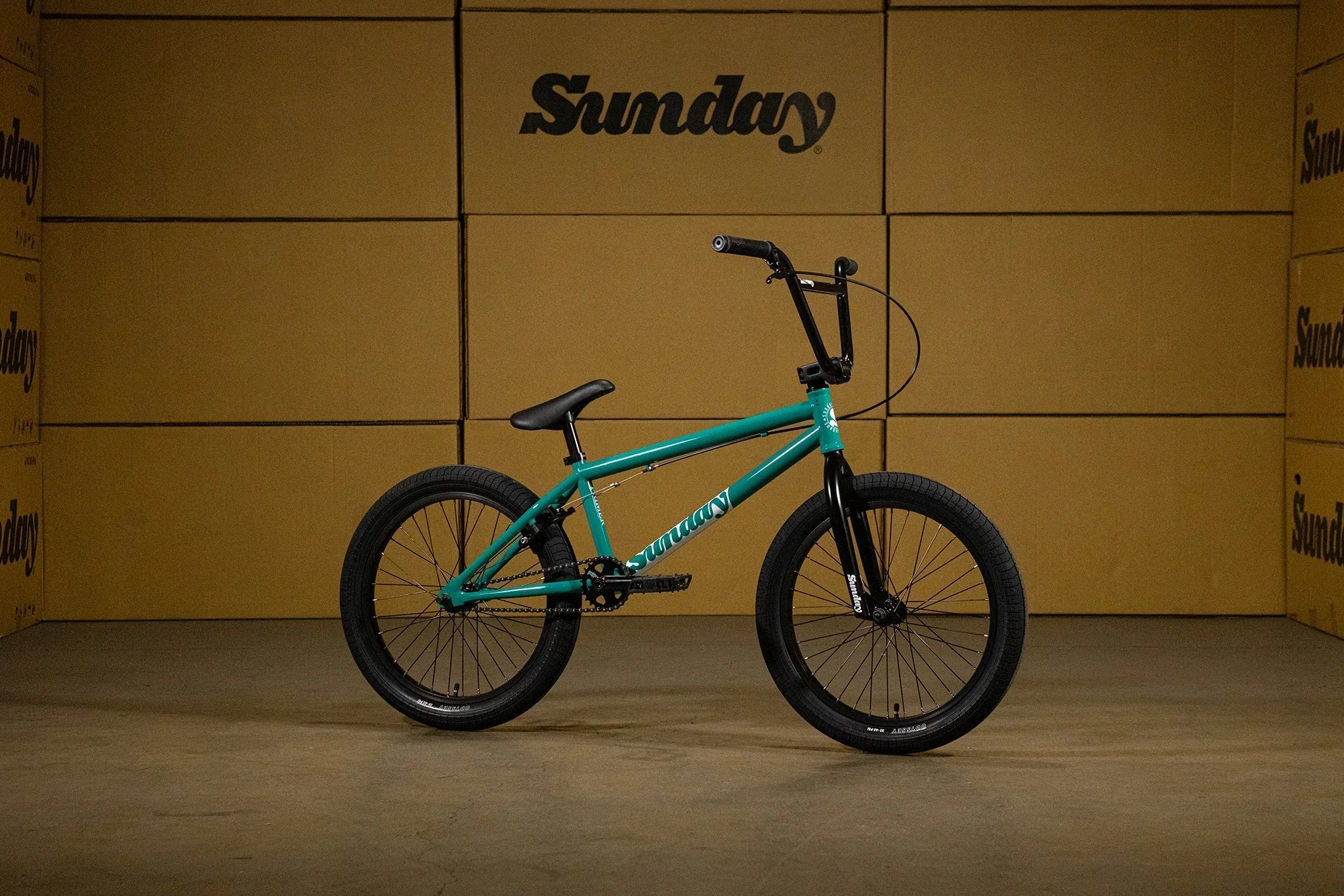 Vélo BMX Sunday turquoise sur fond de cartons de livraison.