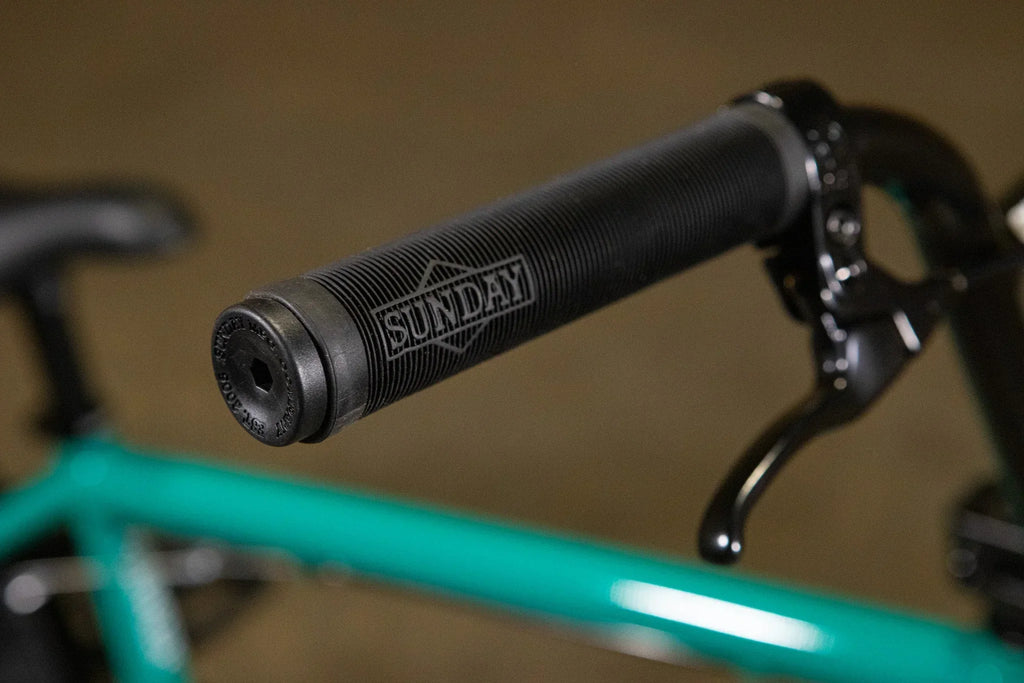 Poignée de guidon BMX noire texturée de marque Sunday sur un vélo turquoise