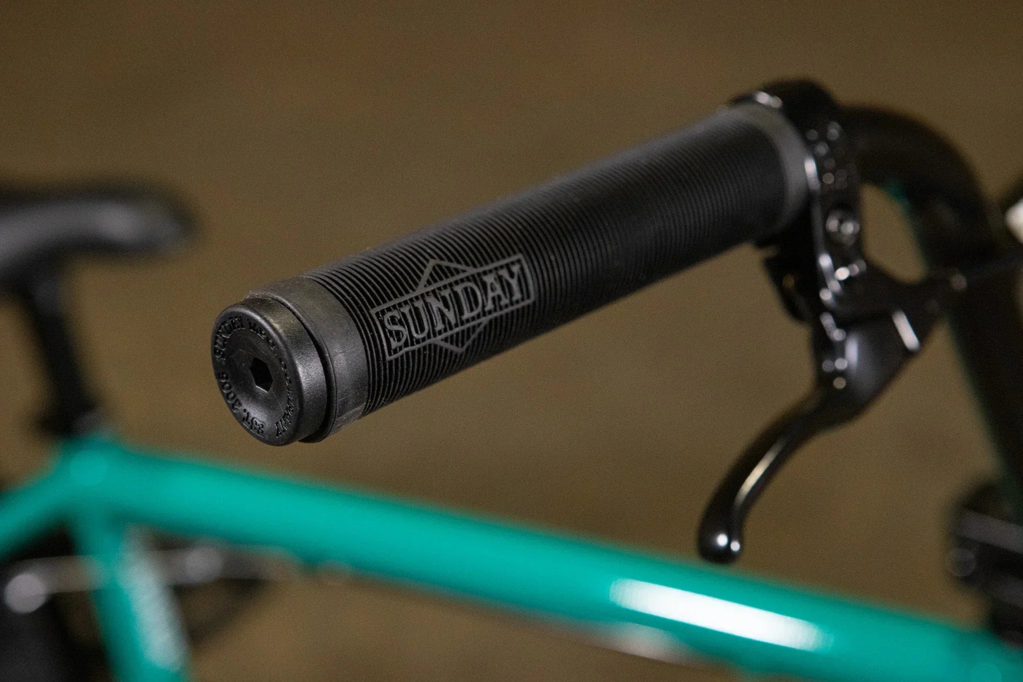 Poignée de guidon BMX noire texturée de marque Sunday sur un vélo turquoise