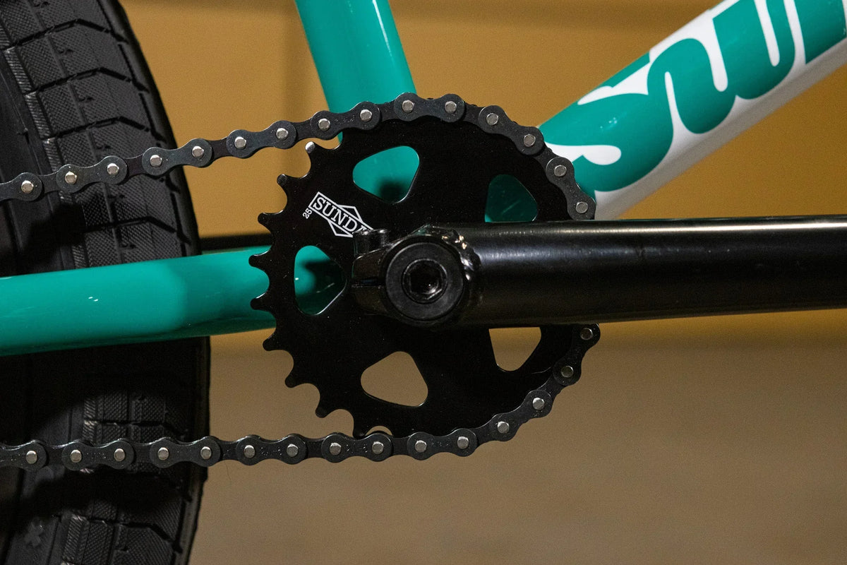 Gros plan d'un plateau de pédalier Sundae noir sur un cadre de BMX vert