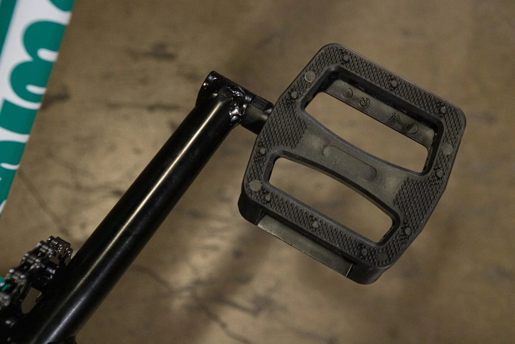 Gros plan d'une pédale de vélo BMX noire en plastique avec surface antidérapante.