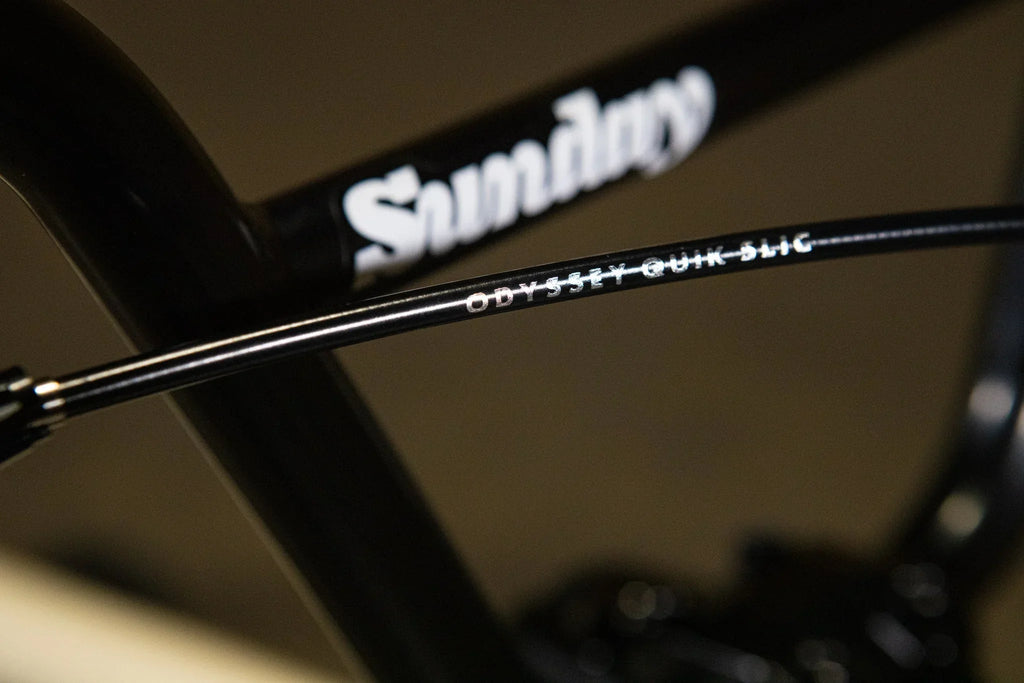 Gros plan d'un câble de frein Odyssey Quik-Slic sur un cadre de vélo BMX Sunday noir