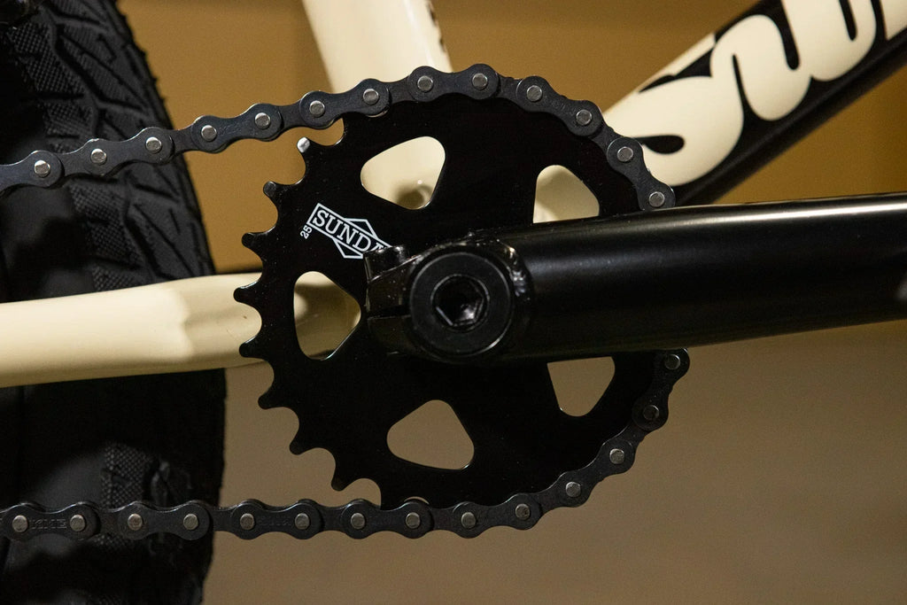 Gros plan d'un plateau de pédalier Sundae noir sur un vélo BMX blanc
