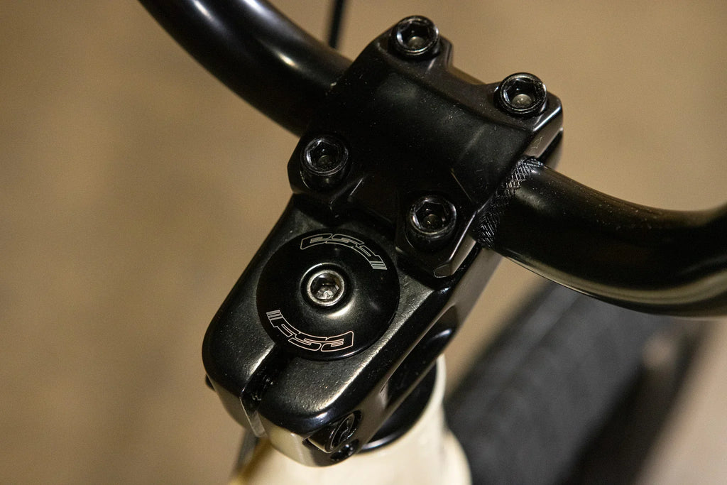 Gros plan d'une potence de vélo BMX noire avec vis de fixation.