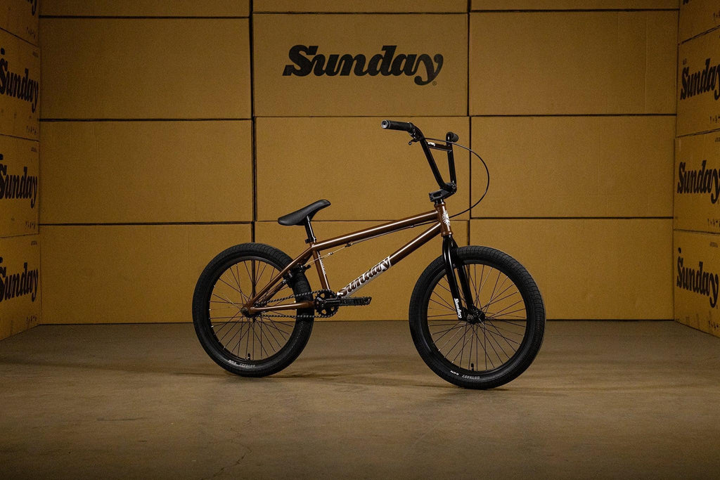 Vélo BMX Sunday marron et noir devant des cartons de marque Sunday