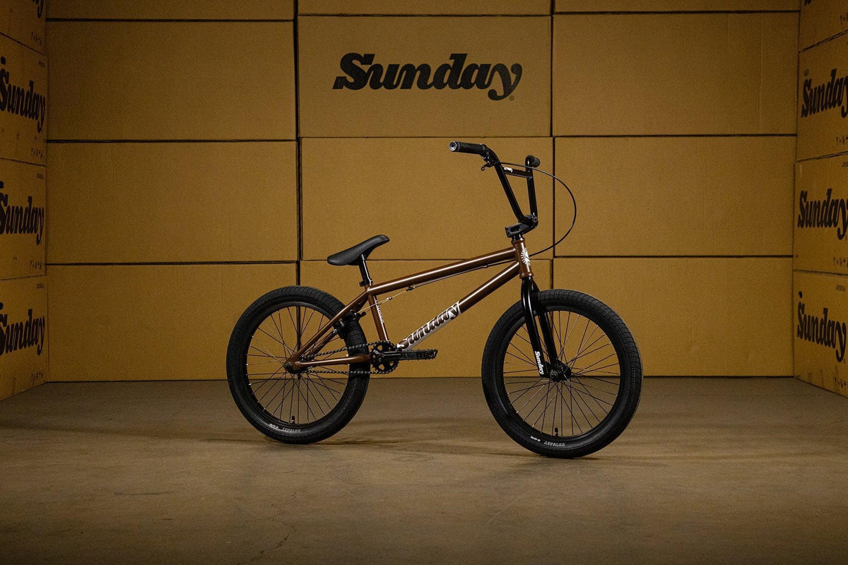 Vélo BMX Sunday marron et noir devant des cartons de marque Sunday
