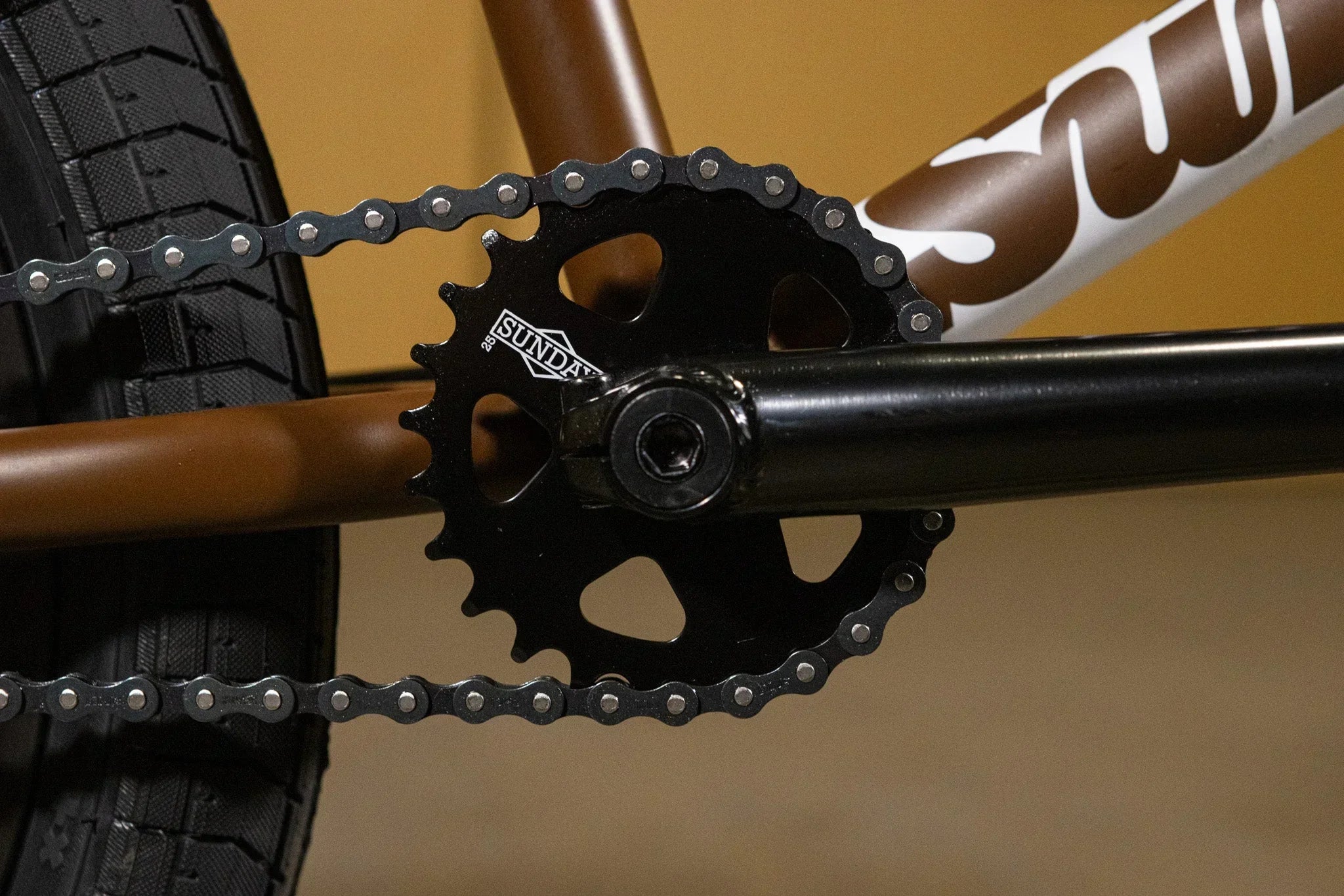 Gros plan du plateau et de la chaîne d'un vélo BMX Sunday marron et noir