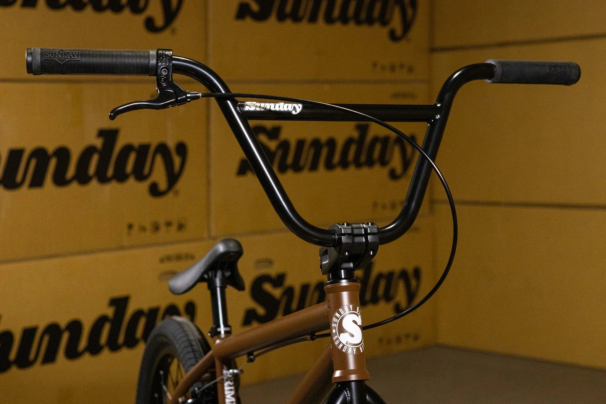 Gros plan du guidon noir d'un vélo BMX Sunday devant des cartons assortis.