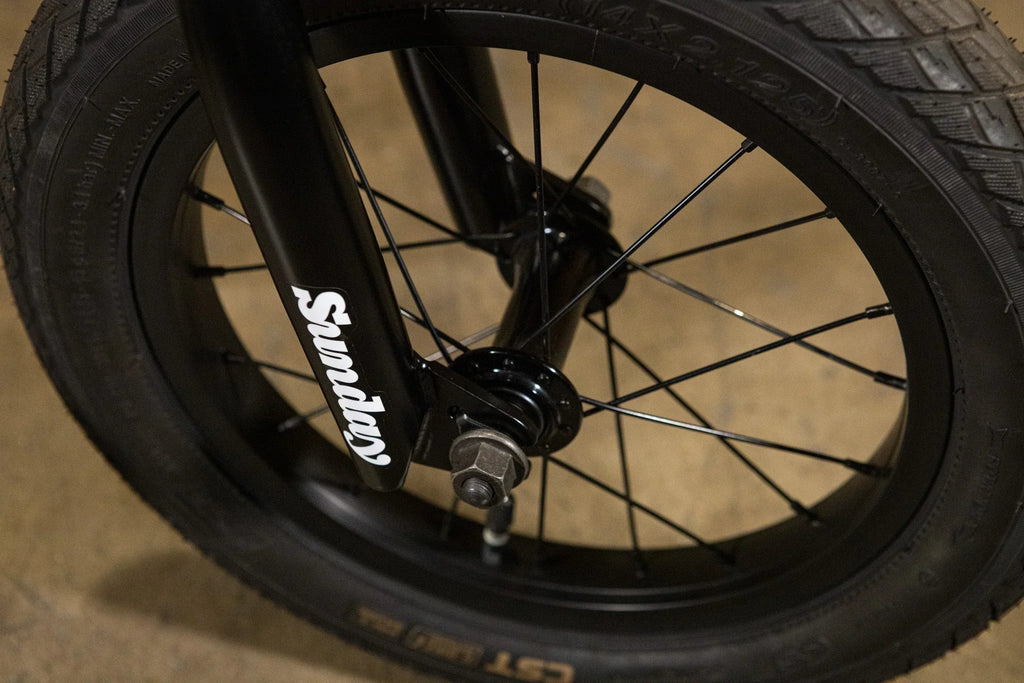 Gros plan d'une roue et d'une fourche de vélo BMX noire avec logo Sunday