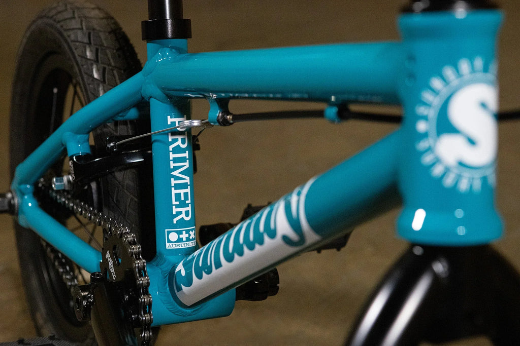 Gros plan du cadre bleu turquoise d'un vélo BMX avec inscriptions Primer et Sunday.