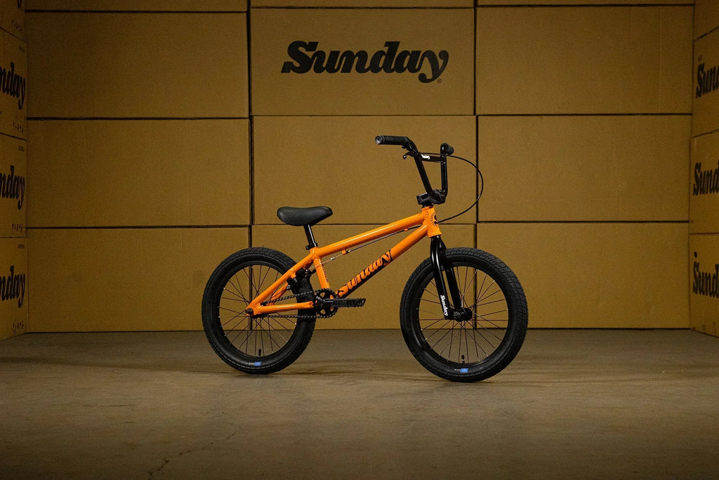 Vélo BMX orange Sunday sur fond de cartons bruns