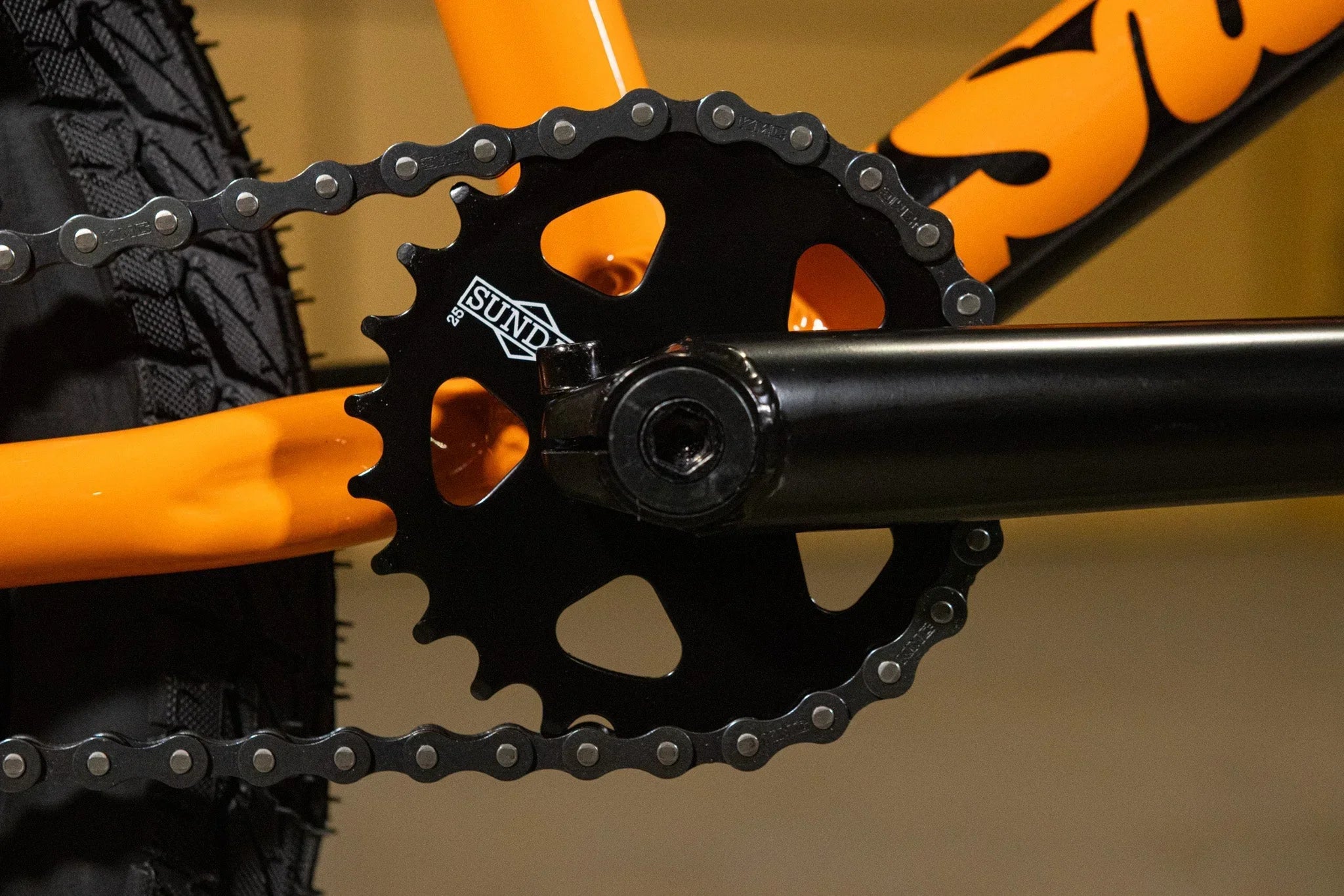 Gros plan d'un plateau de pédalier Sund noir sur un cadre de vélo BMX orange