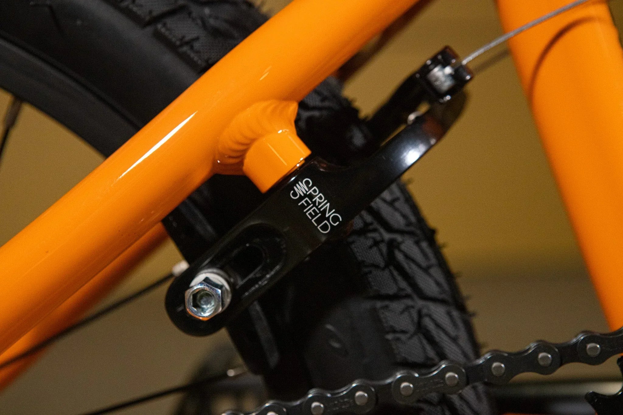 Gros plan d'un tendeur de chaîne Spring Field noir sur un cadre de BMX orange