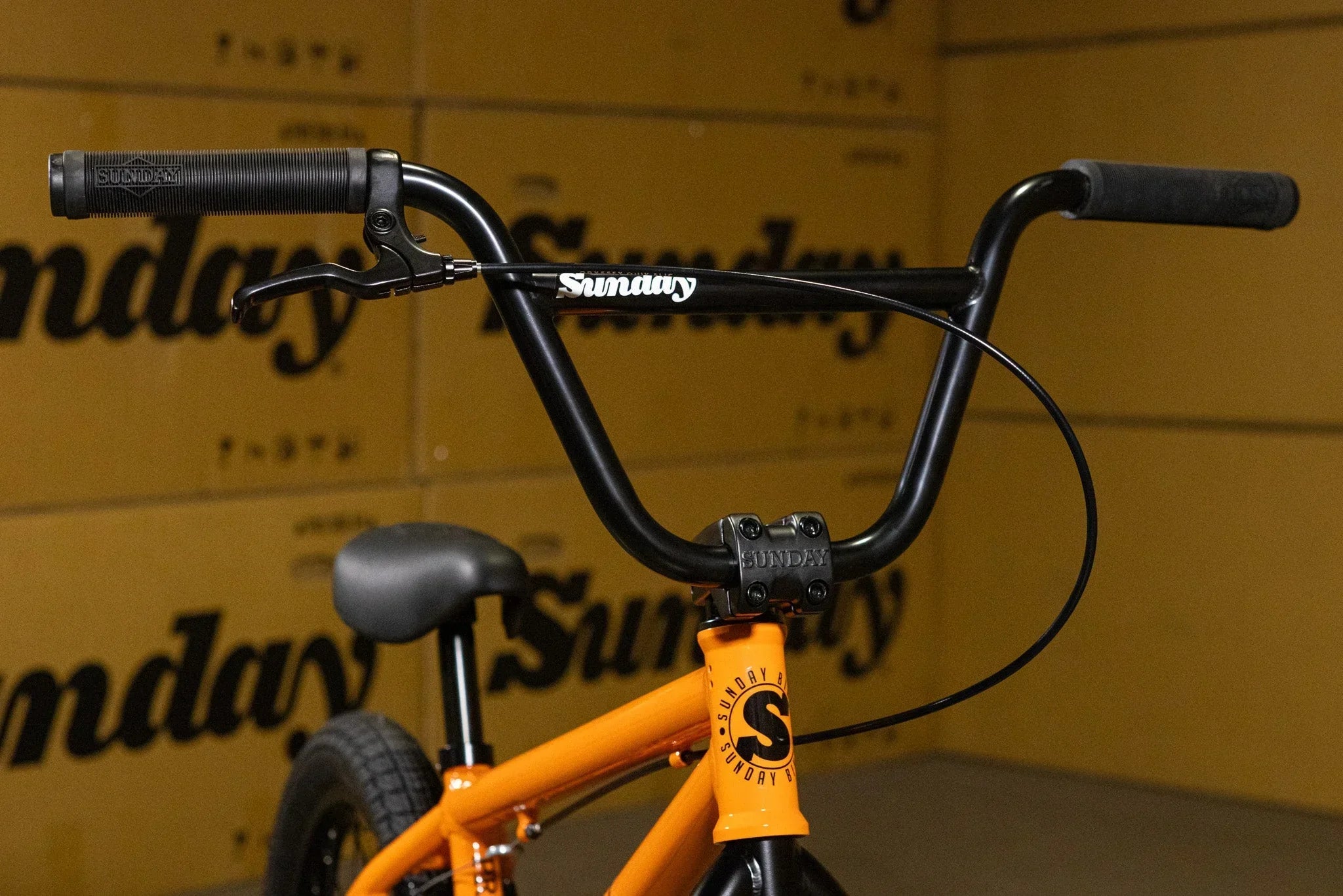 Gros plan du guidon noir et du cadre orange d'un vélo BMX Sunday