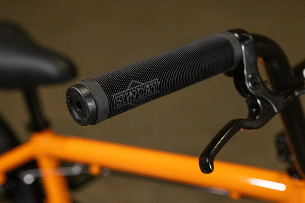 Gros plan d'une poignée de guidon BMX noire Sunday sur un cadre orange.