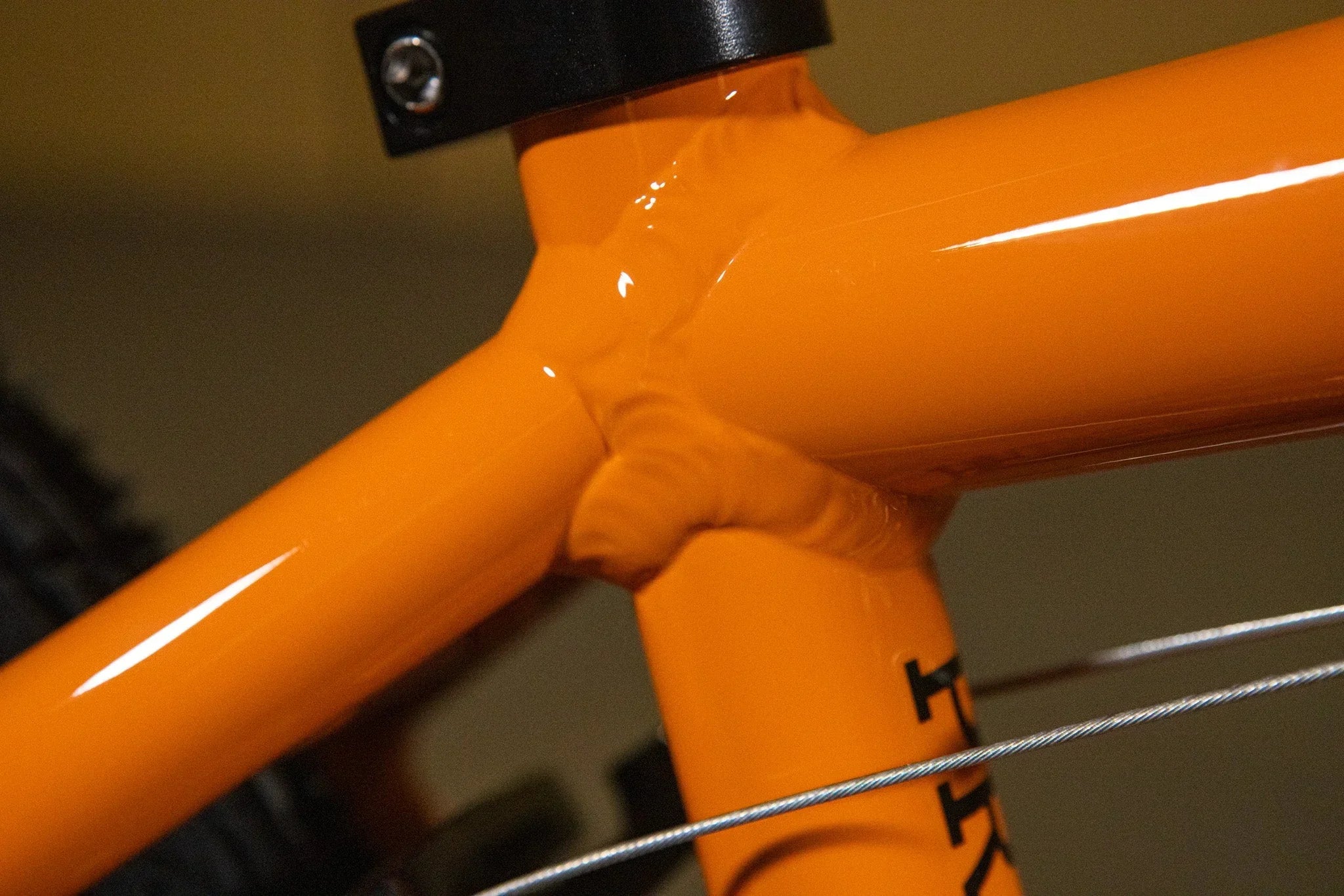 Gros plan des soudures d'un cadre de vélo BMX orange vif.