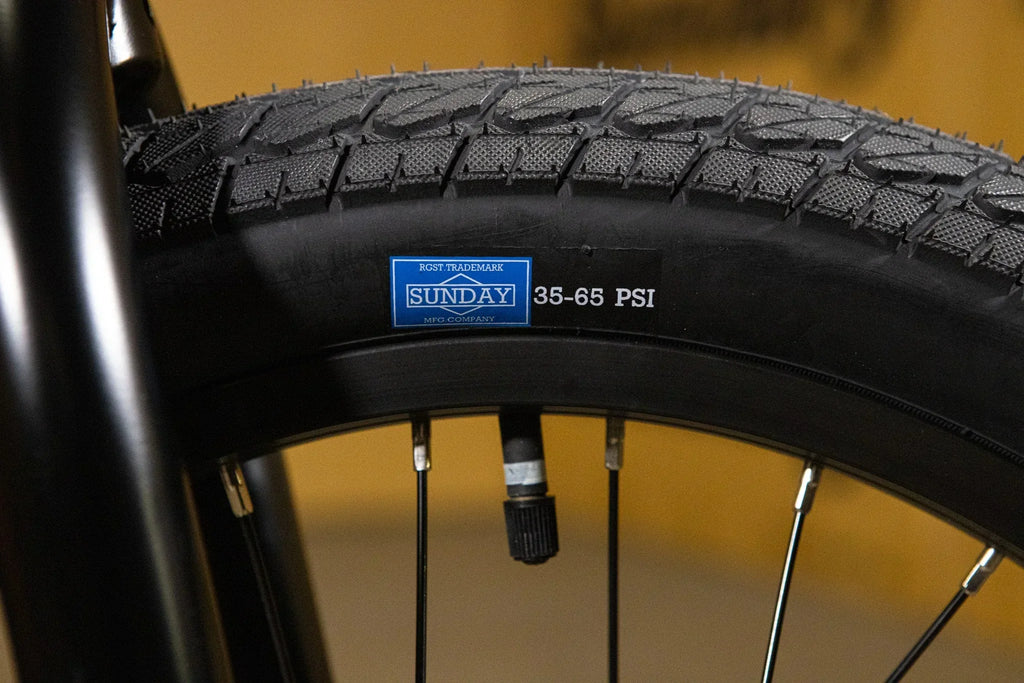 Gros plan d'un pneu de vélo BMX Sunday avec indication de pression 35-65 PSI.