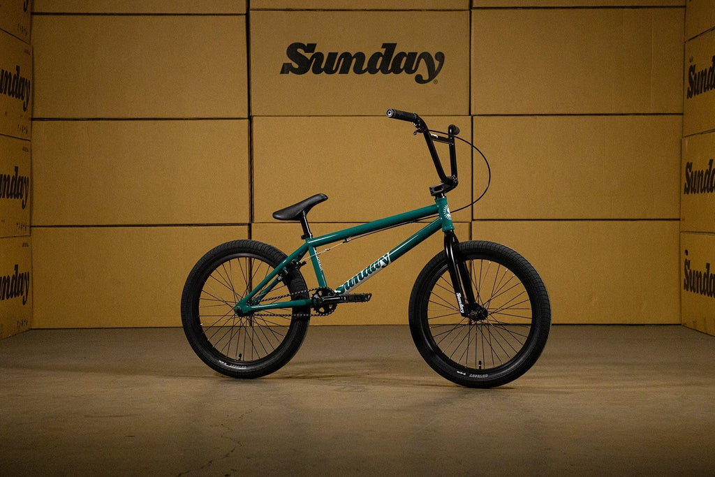 Vélo BMX Sunday vert foncé sur fond de cartons bruns