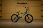 Vélo BMX Sunday vert foncé sur fond de cartons bruns