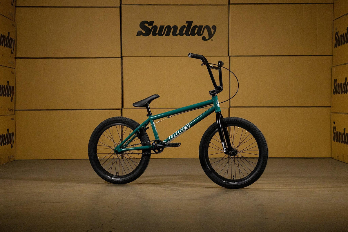Vélo BMX Sunday vert foncé sur fond de cartons bruns