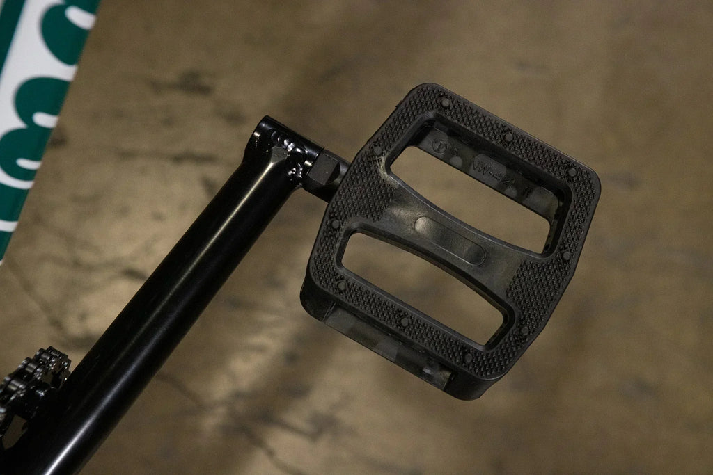 Gros plan d'une pédale de BMX noire en plastique avec surface antidérapante