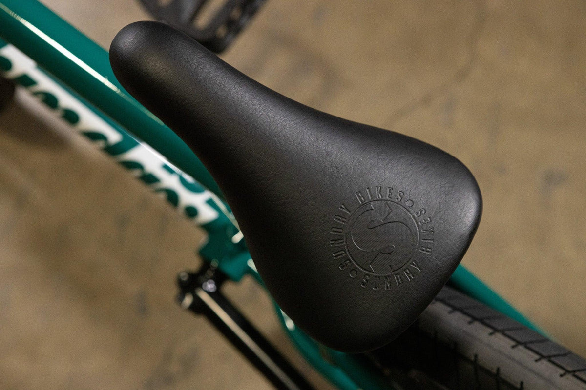 Gros plan d'une selle de vélo BMX noire avec logo embossé sur cadre vert