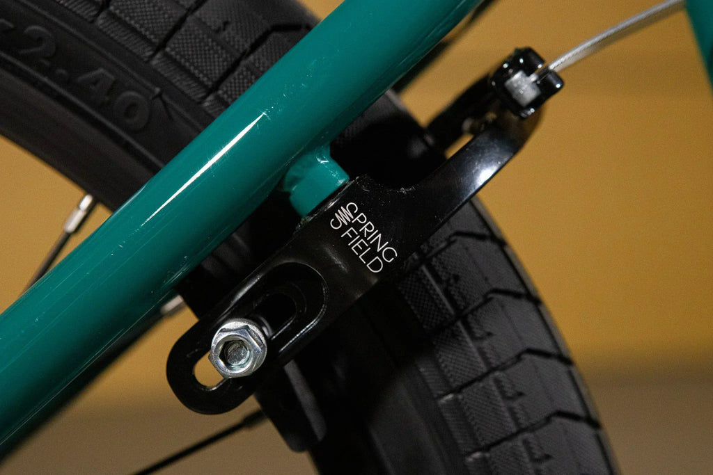 Gros plan d'un tendeur de chaîne Springfield noir sur un cadre de vélo BMX vert.