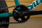 Gros plan d'un plateau Sund noir et d'une chaîne sur un cadre de vélo BMX vert.