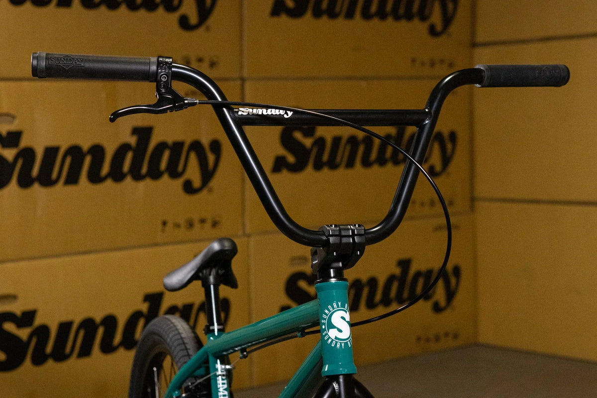 Gros plan sur le guidon noir et le cadre vert d'un vélo BMX Sunday.