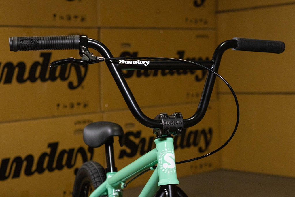 Gros plan du guidon noir et du cadre vert menthe d'un vélo BMX Sunday