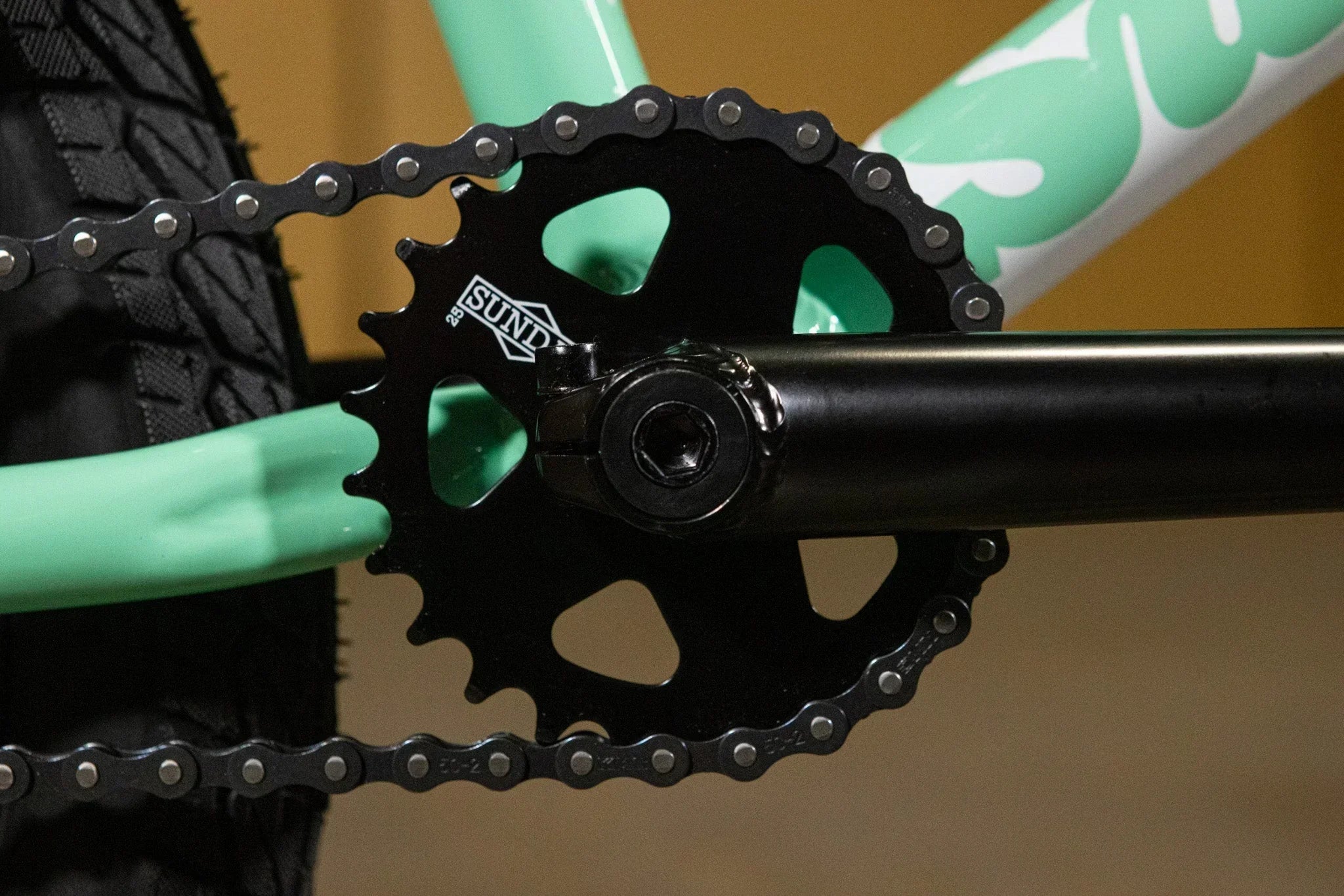 Gros plan d'un plateau SUND noir sur un cadre de vélo BMX vert menthe