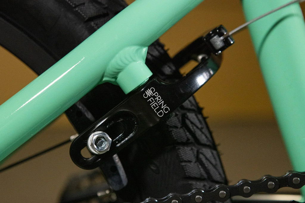 Détail d'un tendeur de chaîne Spring Field noir sur un cadre de BMX vert menthe