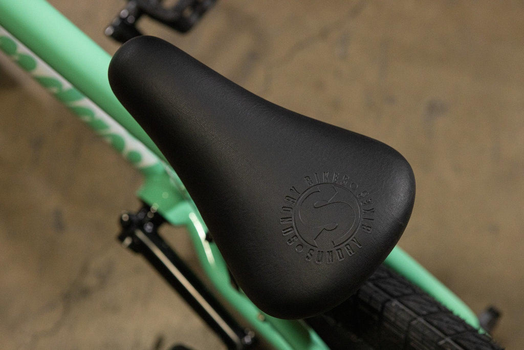 Selle de vélo BMX noire avec logo Sundry sur un cadre vert menthe.