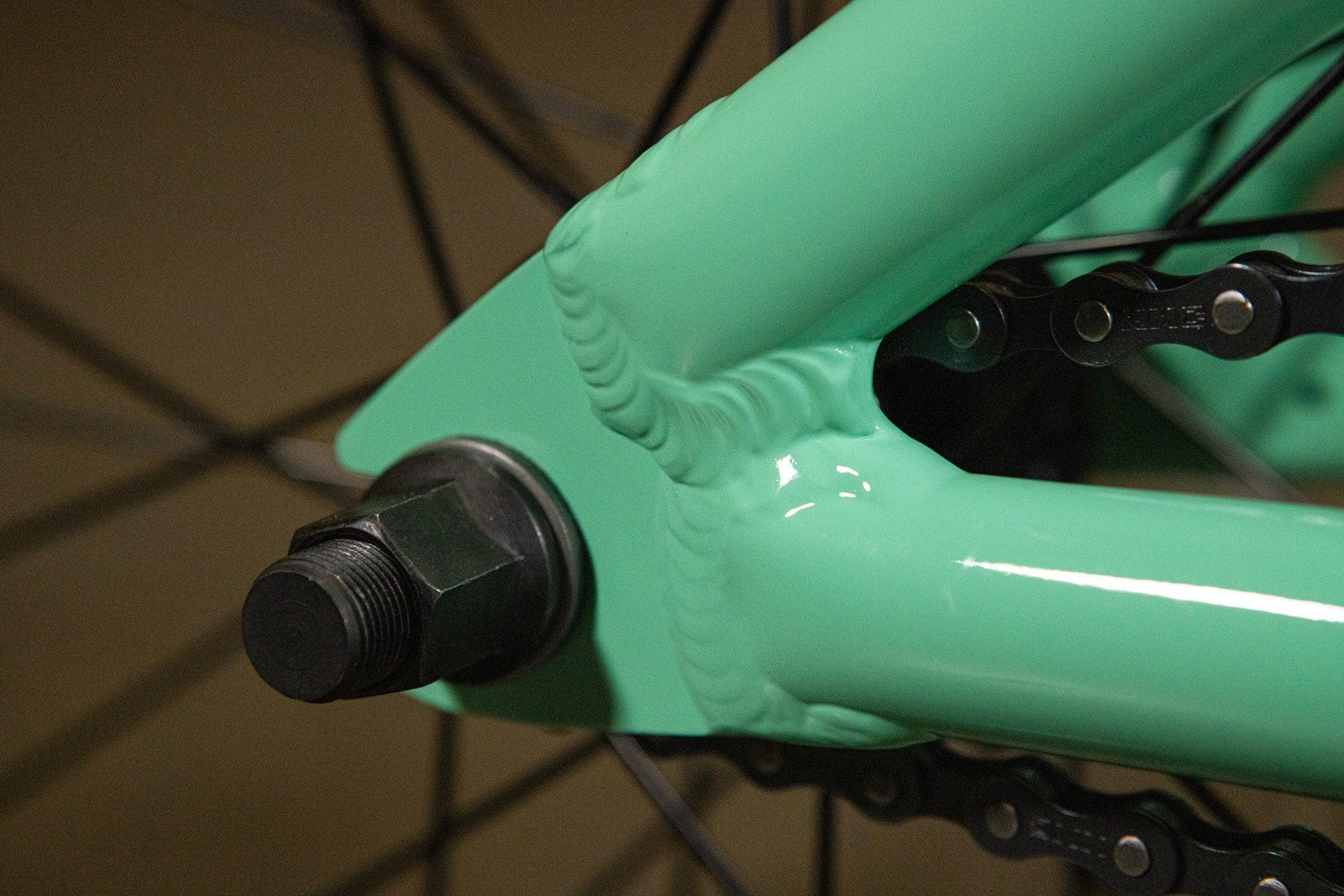 Détail des soudures et de l'axe arrière d'un cadre de vélo BMX vert menthe