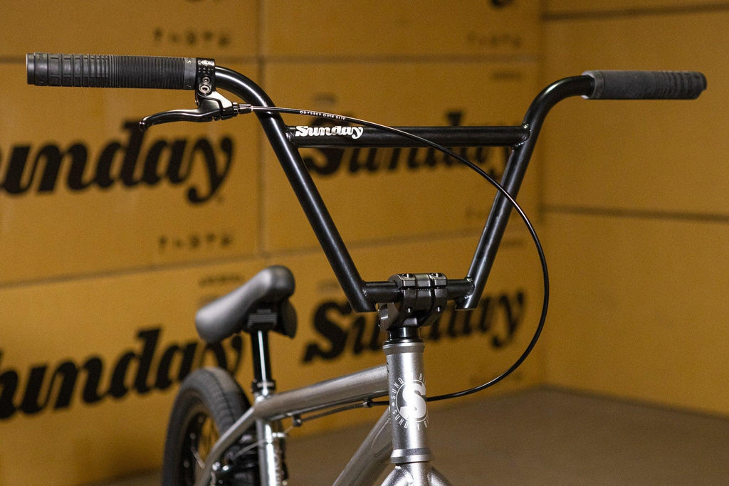 Gros plan sur le guidon noir d'un vélo BMX Sunday avec poignées et câbles de frein.