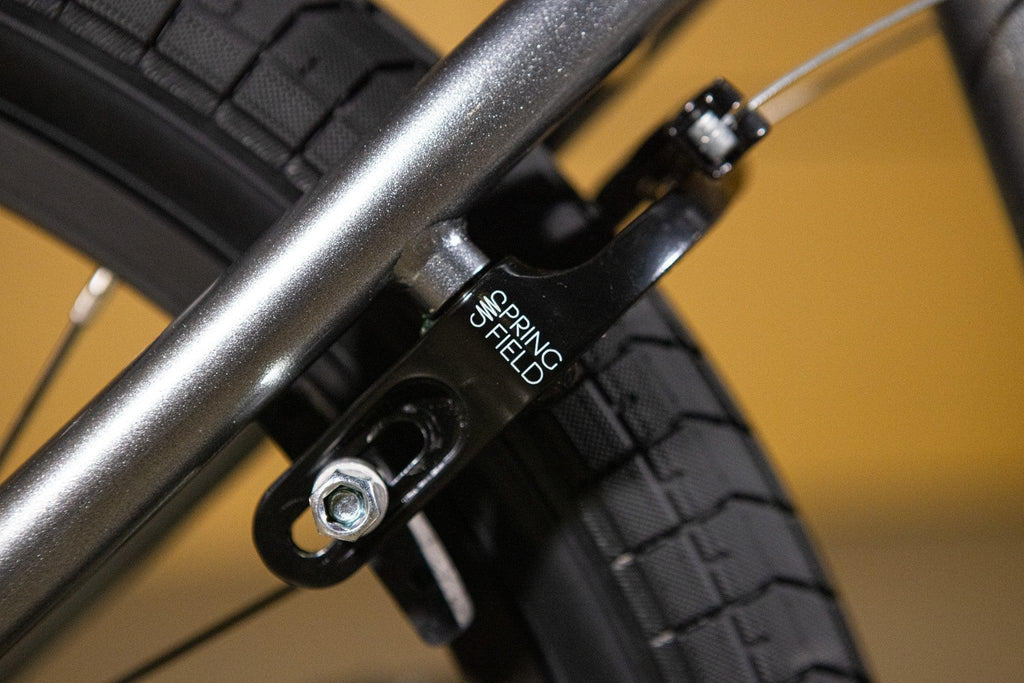 Gros plan d'un tendeur de chaîne Spring Field noir installé sur un cadre de vélo BMX gris.