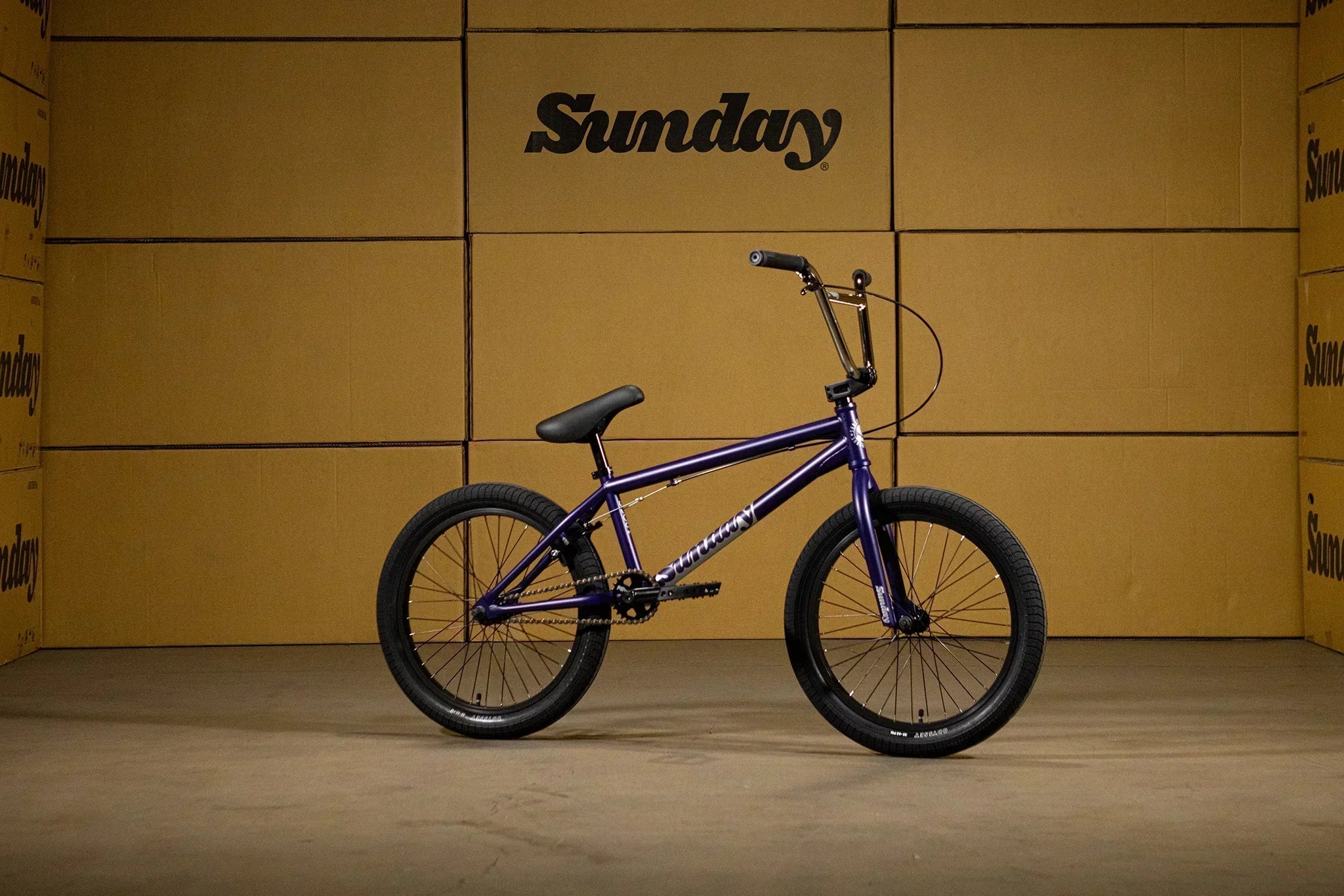 Vélo BMX Sunday violet sur fond de cartons bruns
