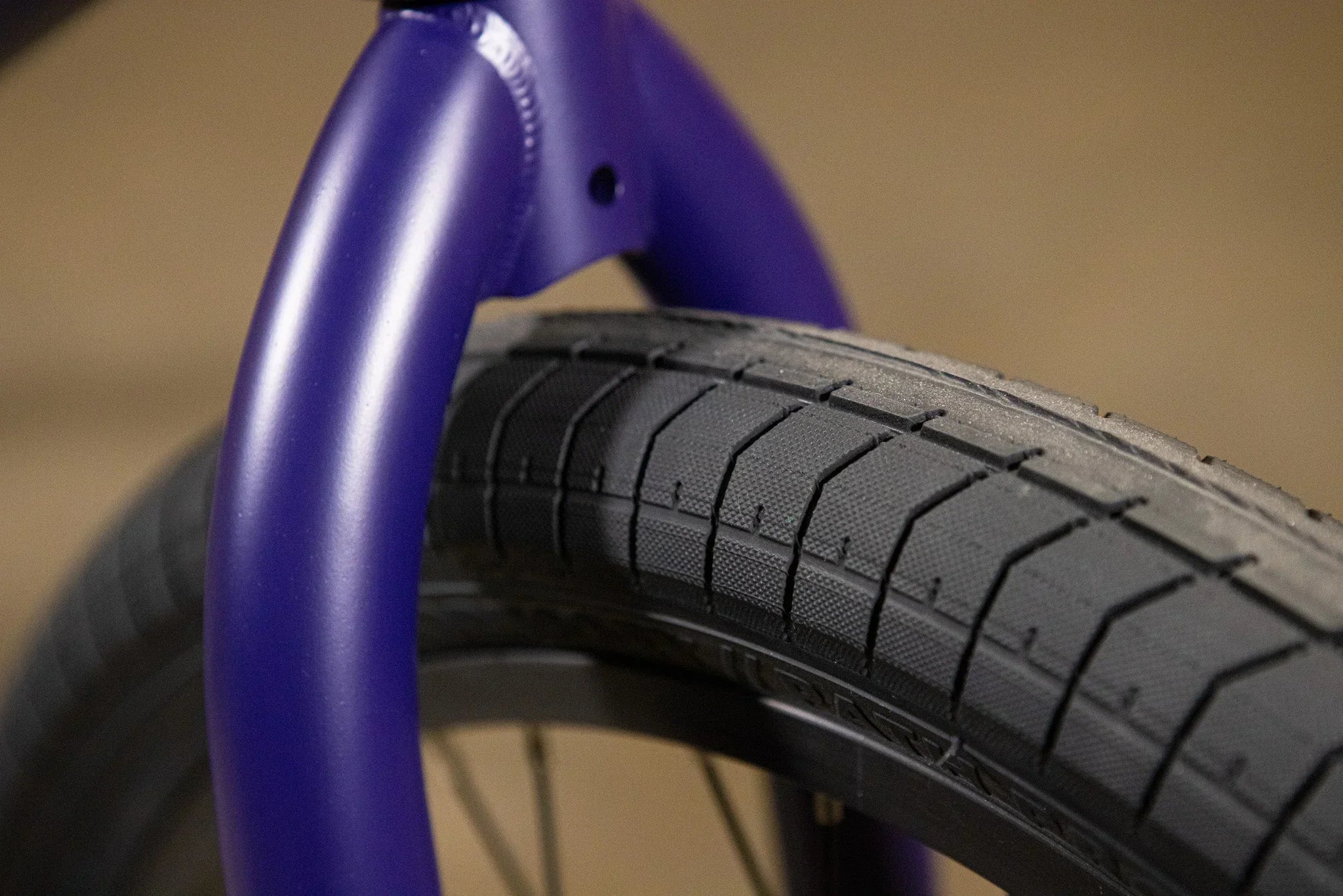 Gros plan d'une fourche de vélo BMX violette et d'un pneu noir texturé