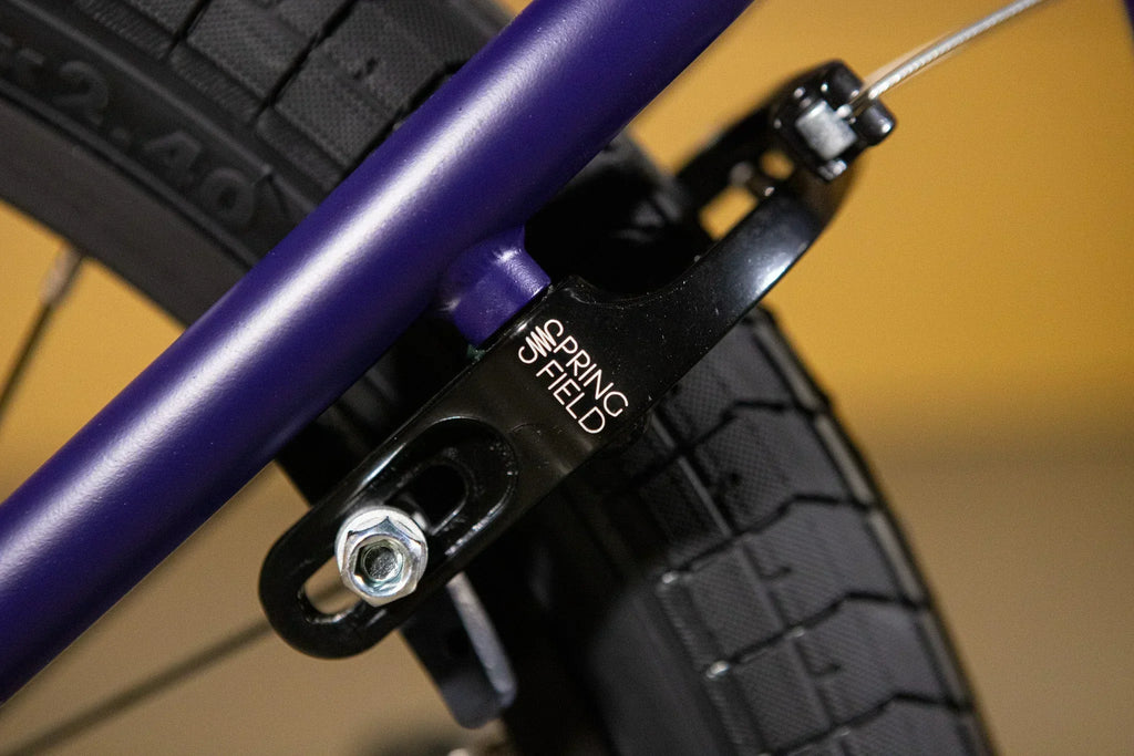 Gros plan d'un frein Springfield noir monté sur un cadre de vélo BMX violet.