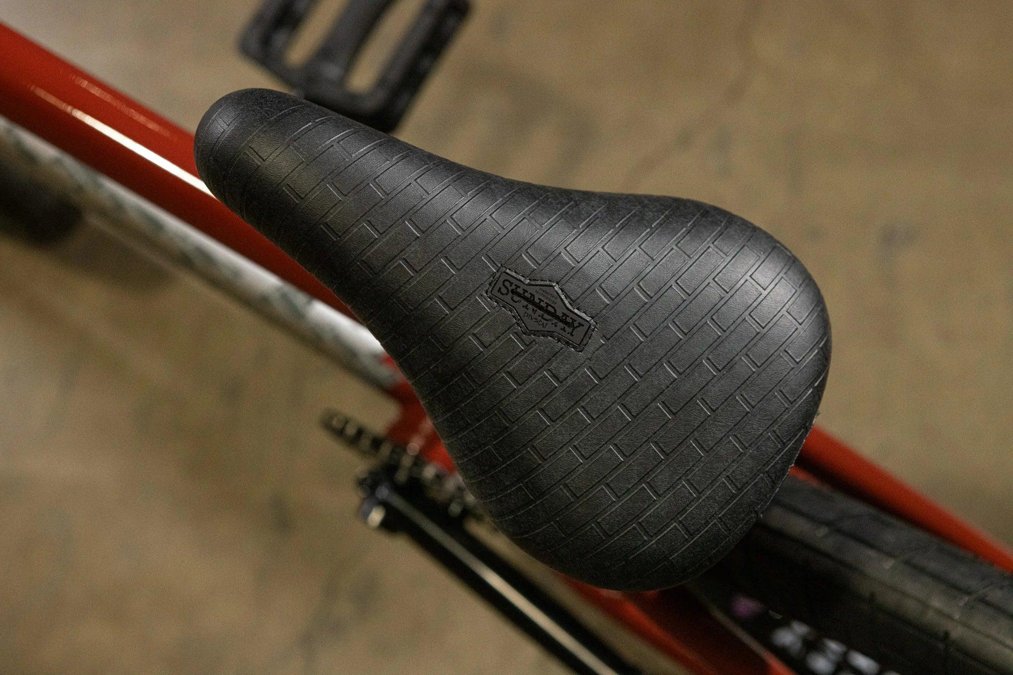 Selle de vélo BMX noire texturée avec logo Sunday sur cadre rouge
